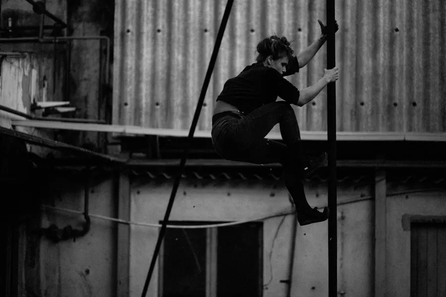 Ilustrasi mimpi akrobat — a woman is hanging upside down on a pole