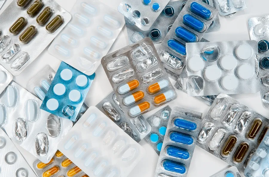 Ilustrasi mimpi apotik — a pile of pills sitting next to each other on top of a table