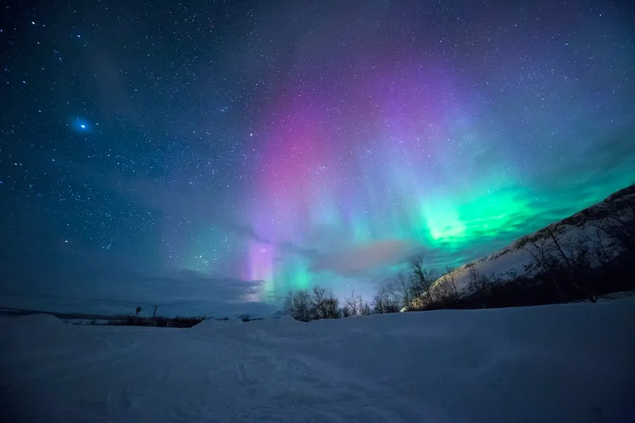 Ilustrasi mimpi aurora — northern lights over snow-capped mountian