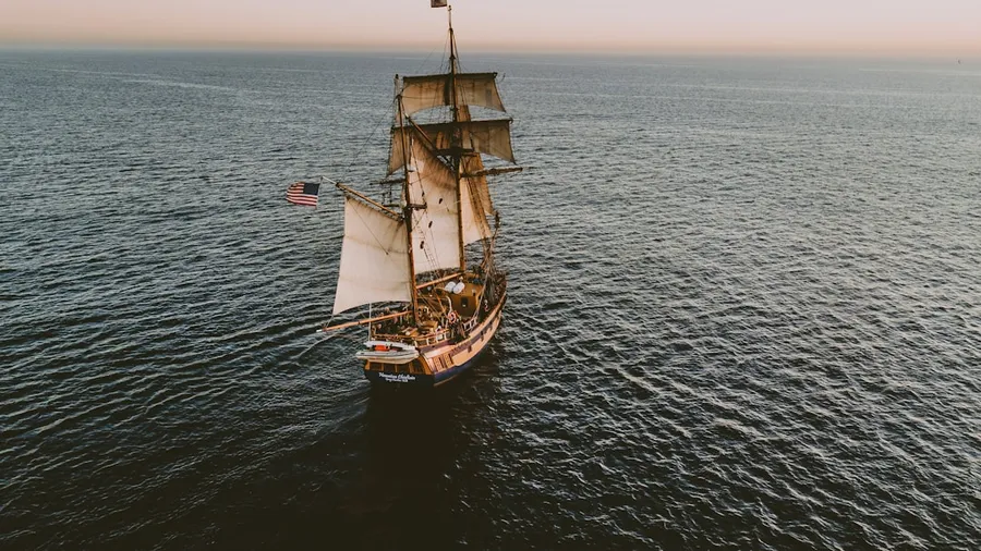 Ilustrasi mimpi bajak laut — brown sailboat in beach under white sky