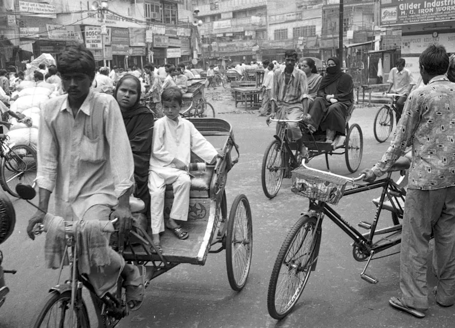 Ilustrasi mimpi balap becak — People on bicycles and a rickshaw in a busy street.