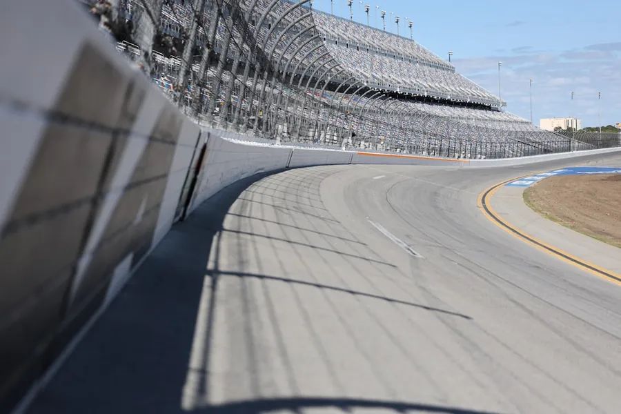 Ilustrasi mimpi balap mobil — A racetrack curve and grandstands are shown.