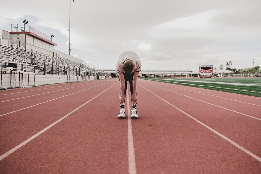 Ilustrasi mimpi balapan — man in black shorts running on track field during daytime