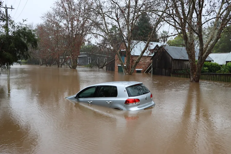 Ilustrasi mimpi banjir besar — a car driving through a flooded street