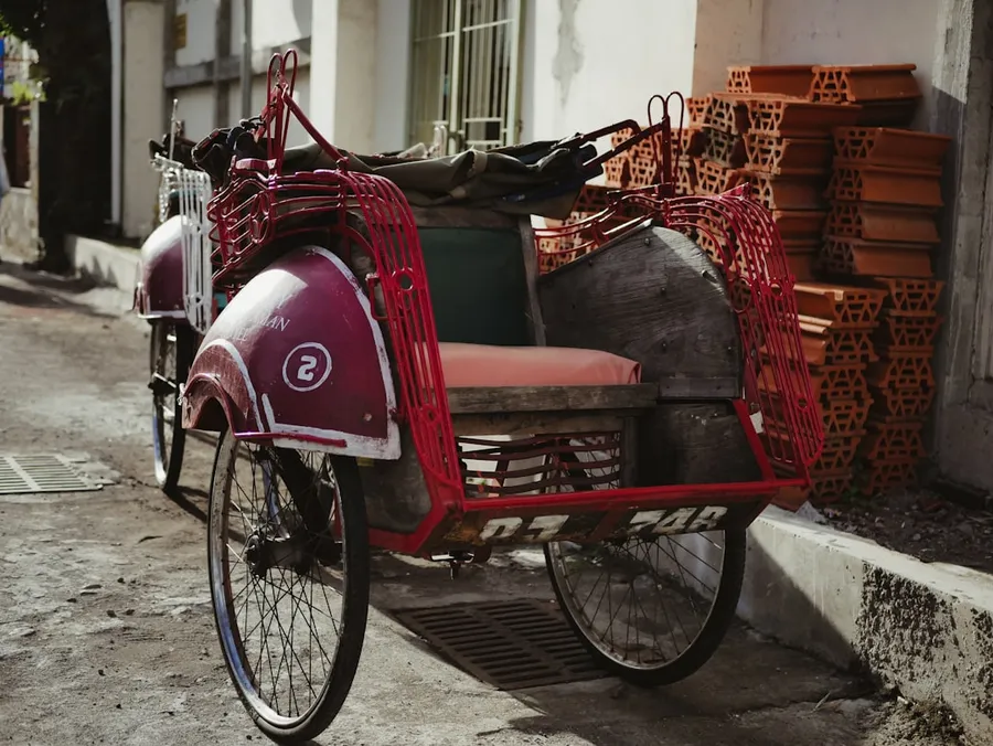 Ilustrasi mimpi becak — red and black bicycle on gray concrete floor