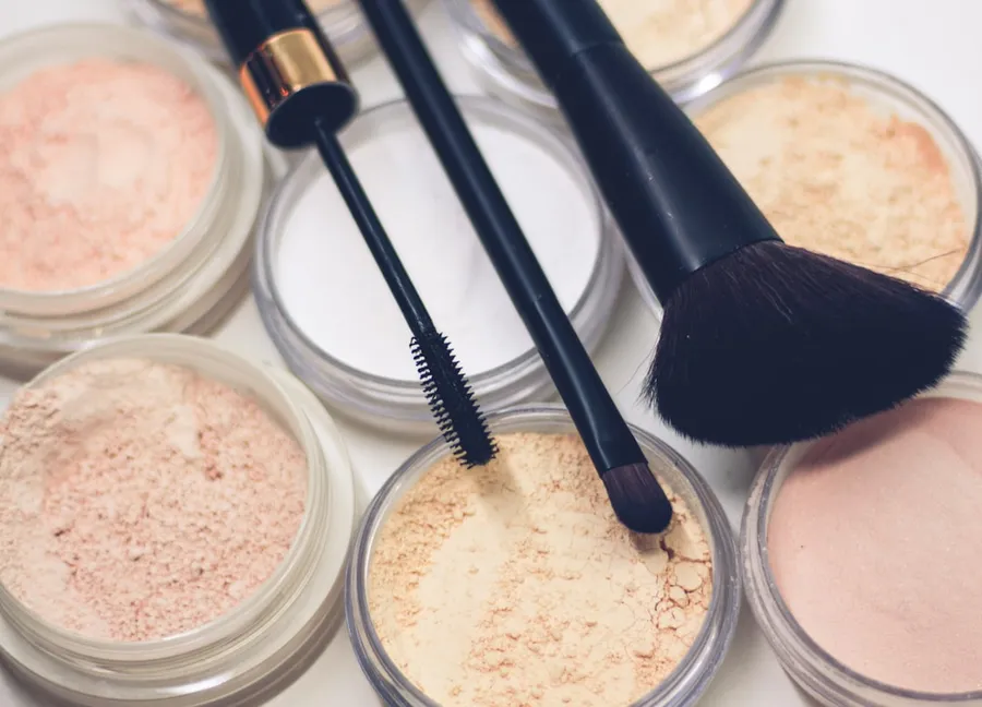 Ilustrasi mimpi bedak — three makeup brushes on top of compact powders