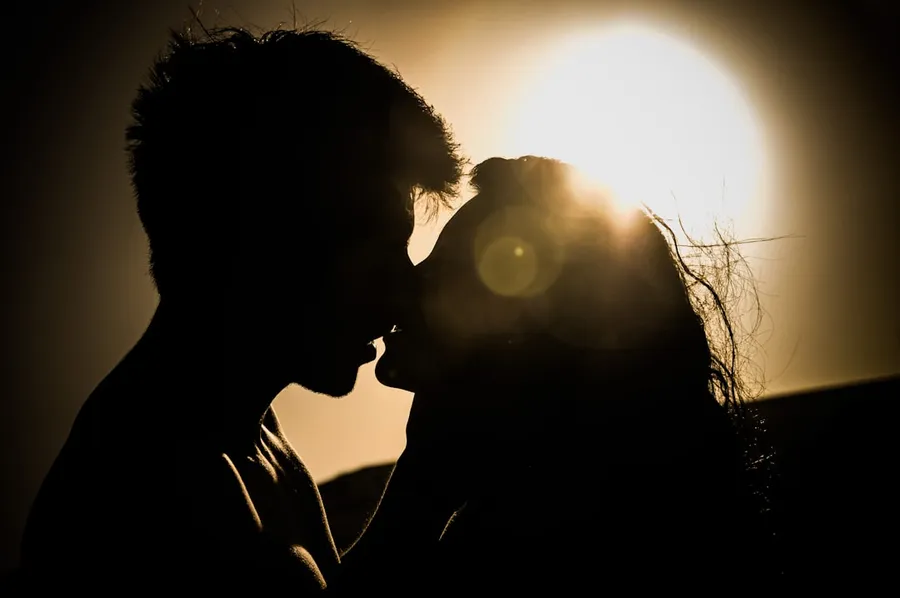 Ilustrasi mimpi berciuman — man and woman kissing under the sun