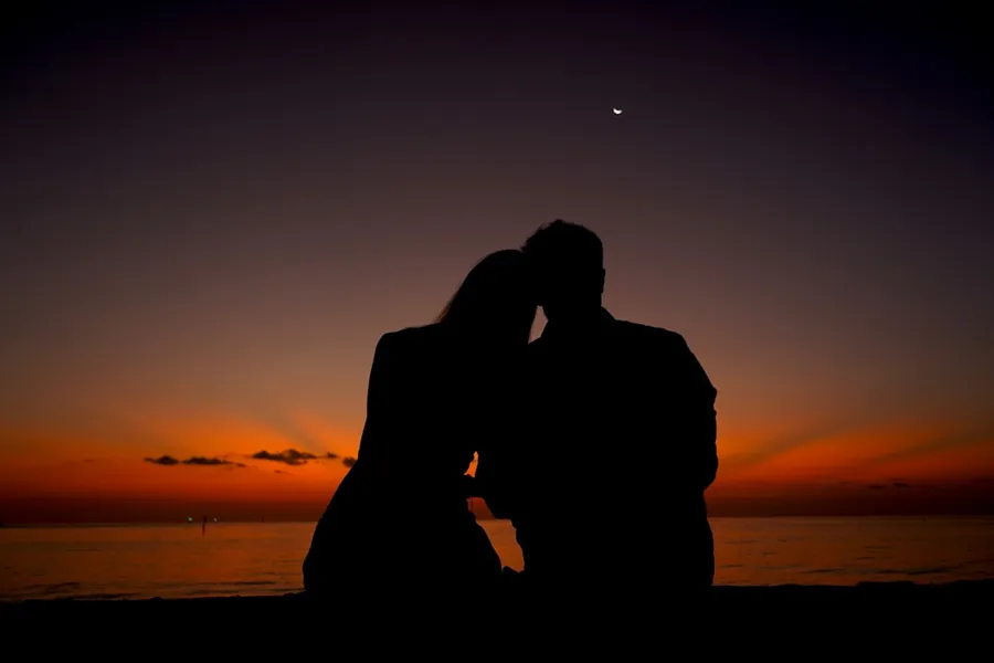 Ilustrasi mimpi bersetubuh — a man and woman kissing at sunset