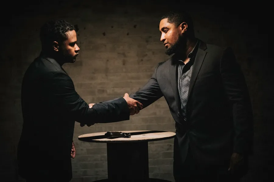 Ilustrasi mimpi bertemu presiden — two men shaking hands in a dark room