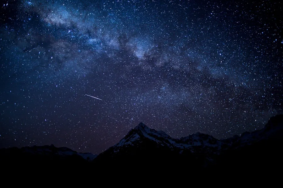 Ilustrasi mimpi bintang jatuh — silhouette of mountain peak at nighttime