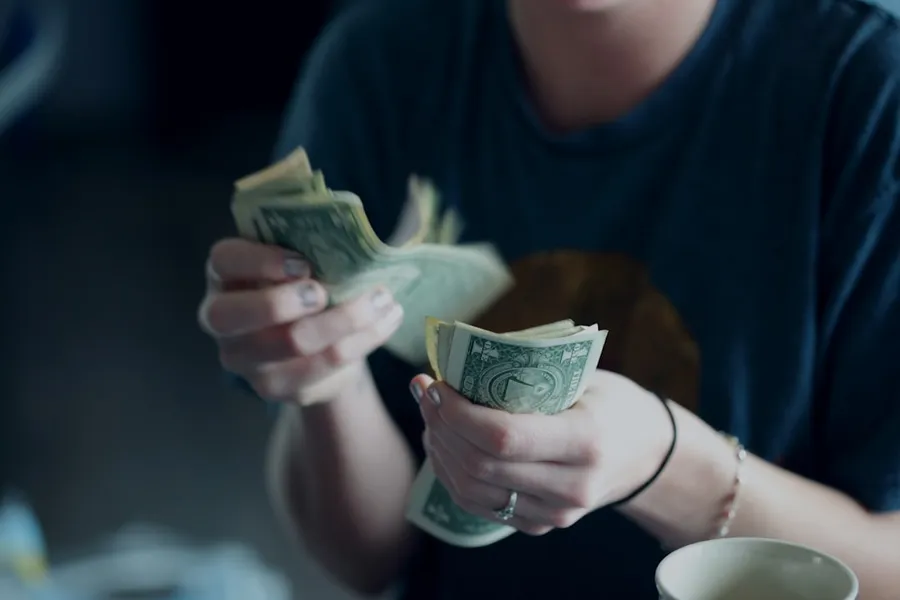 Ilustrasi mimpi cari uang — focus photography of person counting dollar banknotes