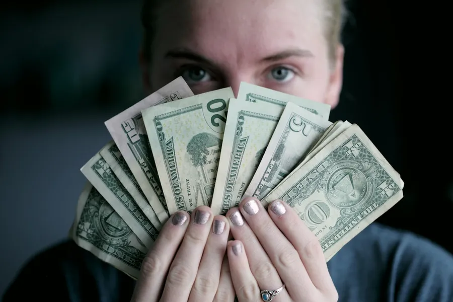 Ilustrasi mimpi dapat uang — person holding fan of U.S. dollars banknote