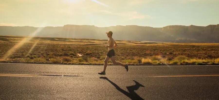 Ilustrasi mimpi dikejar orang — man in black shorts running on gray asphalt road during daytime