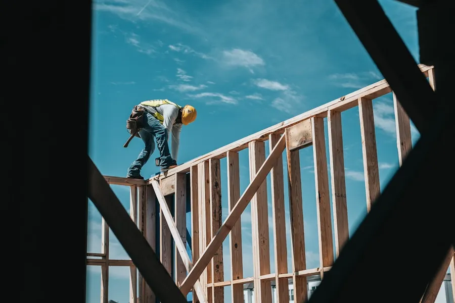 Ilustrasi mimpi dirikan rumah — construction worker in hard hat on building frame