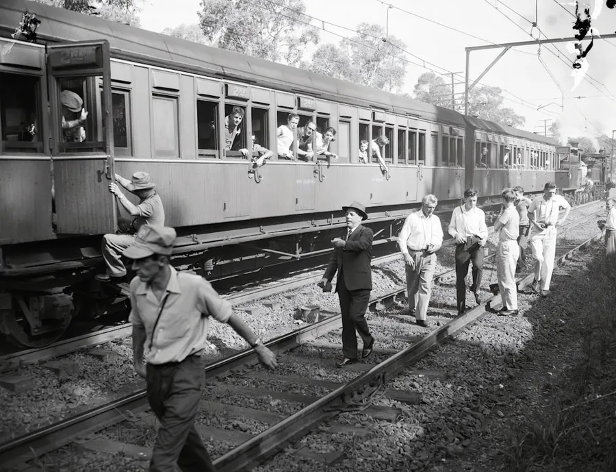 Ilustrasi mimpi dorong kereta — a black and white photo of a group of people walking on a train track