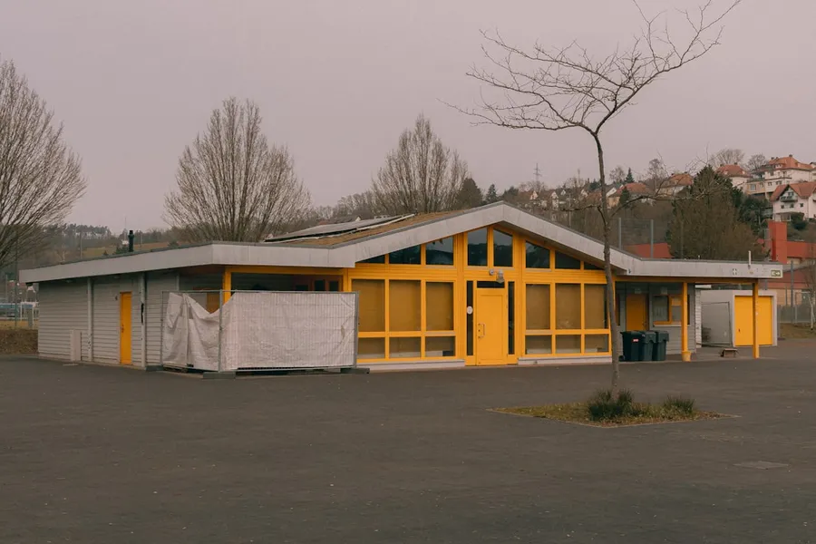 Ilustrasi mimpi fasilitas — A modern building with yellow accents and large windows.