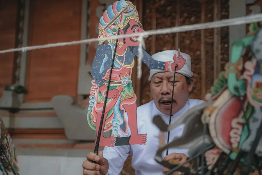 Ilustrasi mimpi gareng — a man is holding up a dragon puppet