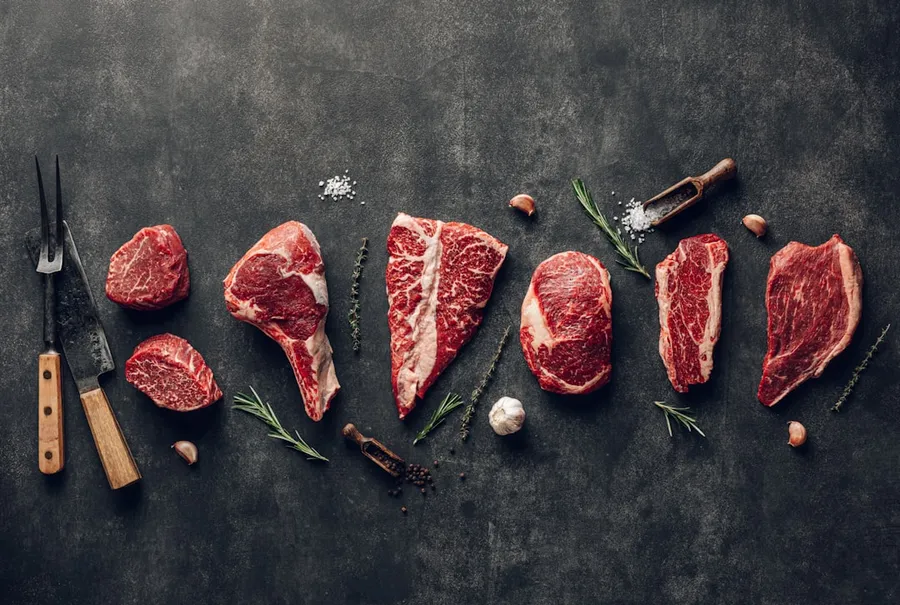 Ilustrasi mimpi garpu daging — raw meat on a table with a knife, garlic and pepper