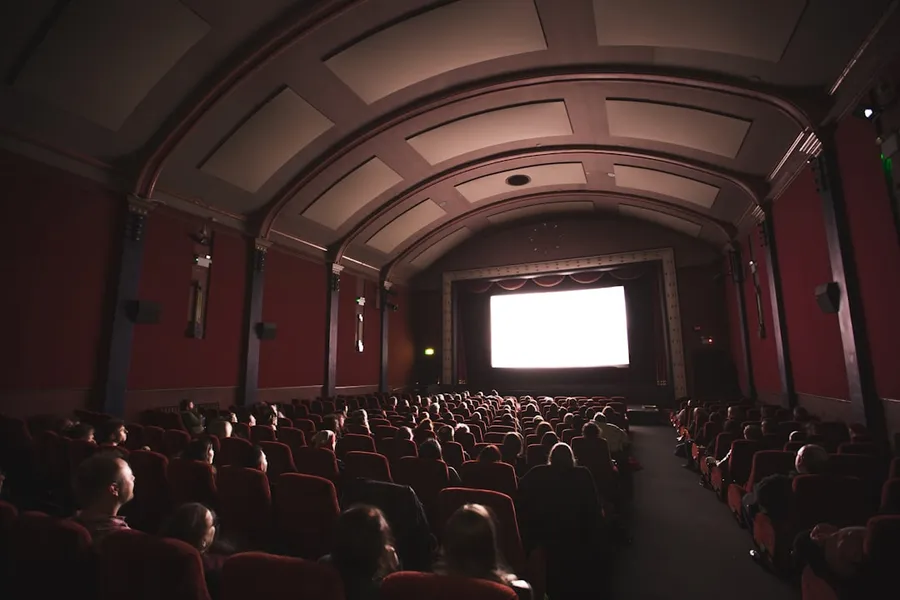 Ilustrasi mimpi gedung bioskop — group of people staring at monitor inside room