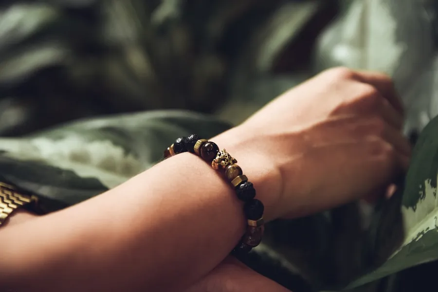 Ilustrasi mimpi gelang tangan — person wearing beaded black bracelet