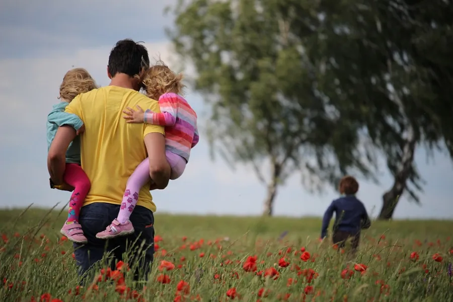 Ilustrasi mimpi gendong anak — man carrying to girls on field of red petaled flower
