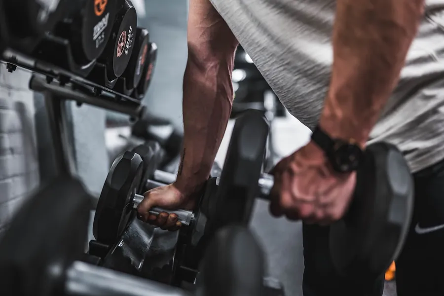 Ilustrasi mimpi gerak badan — person in gray shirt holding black dumbbell