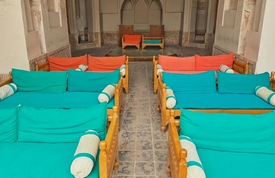 Ilustrasi mimpi guling — Rows of teal and orange cushioned seating indoors.