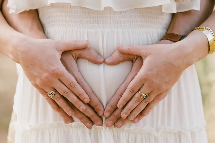 Ilustrasi mimpi hamil kembar — a woman holding her hands in the shape of a heart