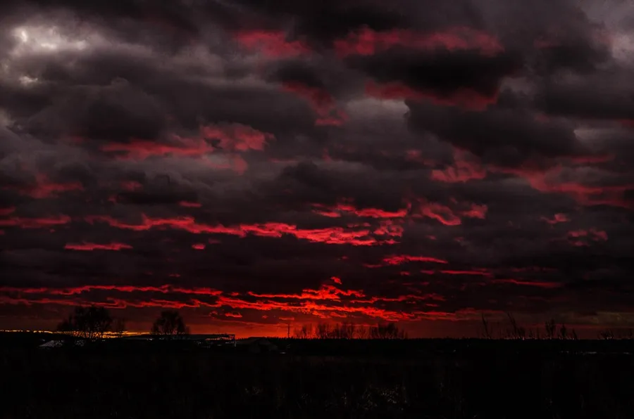 Ilustrasi mimpi hujan darah — a red and black sky with clouds in the background