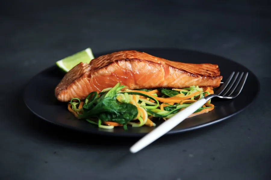 Ilustrasi mimpi ikan bakar — grilled fish, cooked vegetables, and fork on plate