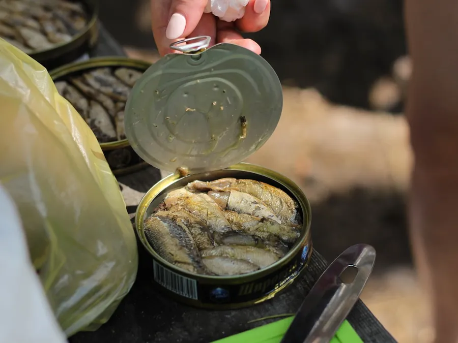 Ilustrasi mimpi ikan kalengan — person holding clear glass jar with yellow powder