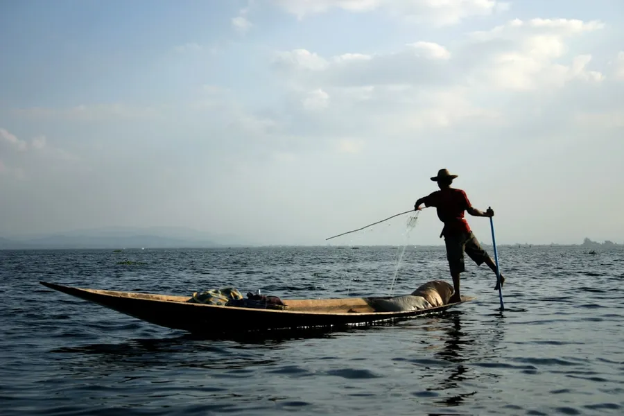 Ilustrasi mimpi ikan sampan — man riding on b oat during daytime