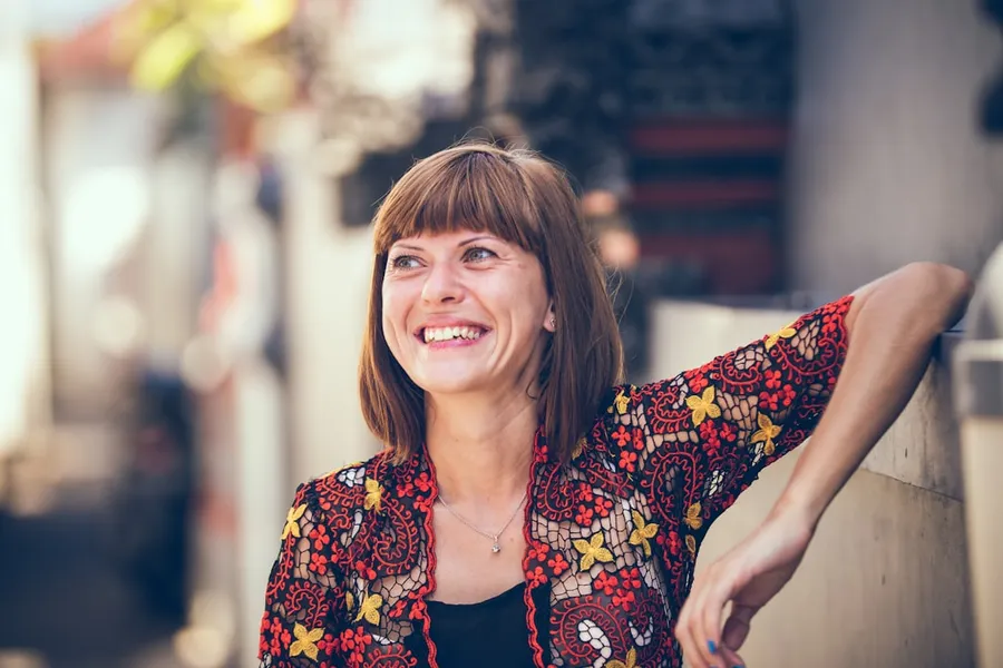 Ilustrasi mimpi istri — woman in floral-themed cardigan leaning on fence in bokeh photography