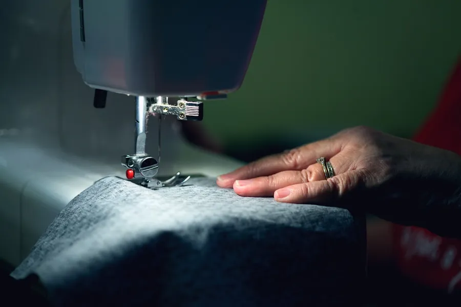 Ilustrasi mimpi jahit baju — person in gray shirt sewing