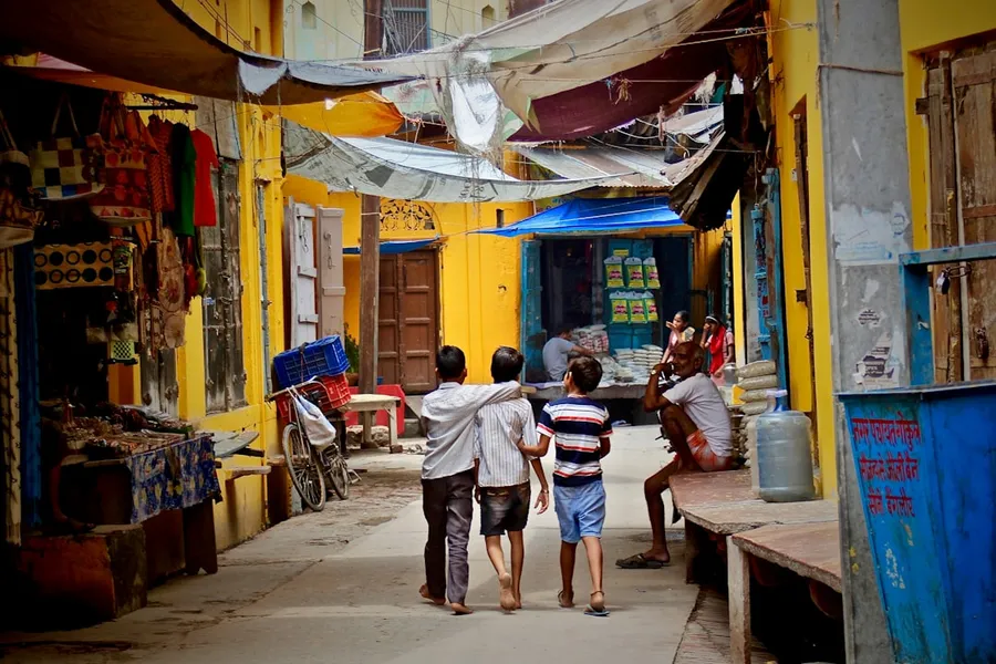 Ilustrasi mimpi jalan-jalan — three boys walking between buildings at daytime