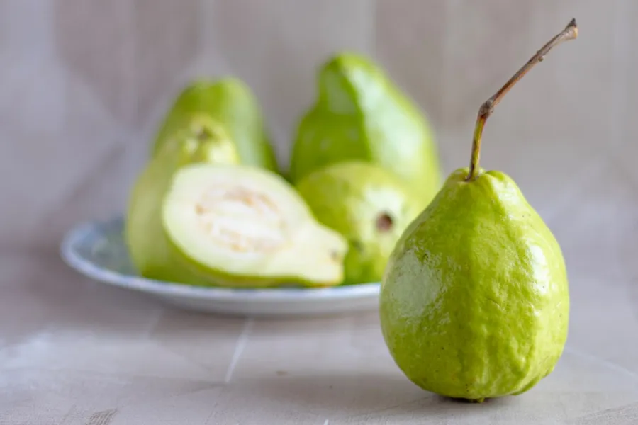 Ilustrasi mimpi jambu — green fruit on white ceramic plate