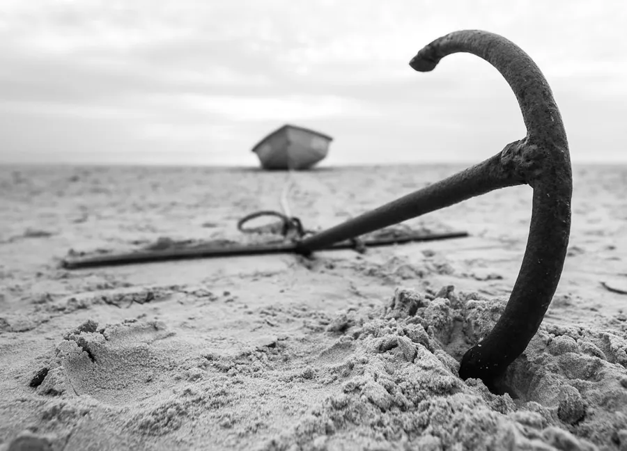 Ilustrasi mimpi jangkar — a broken umbrella sitting on top of a sandy beach