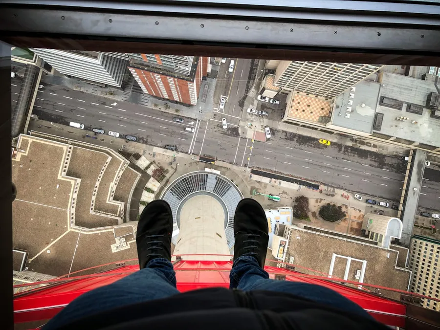 Ilustrasi mimpi jatuh dari ketinggian — person in blue denim jeans and black sneakers sitting on red car