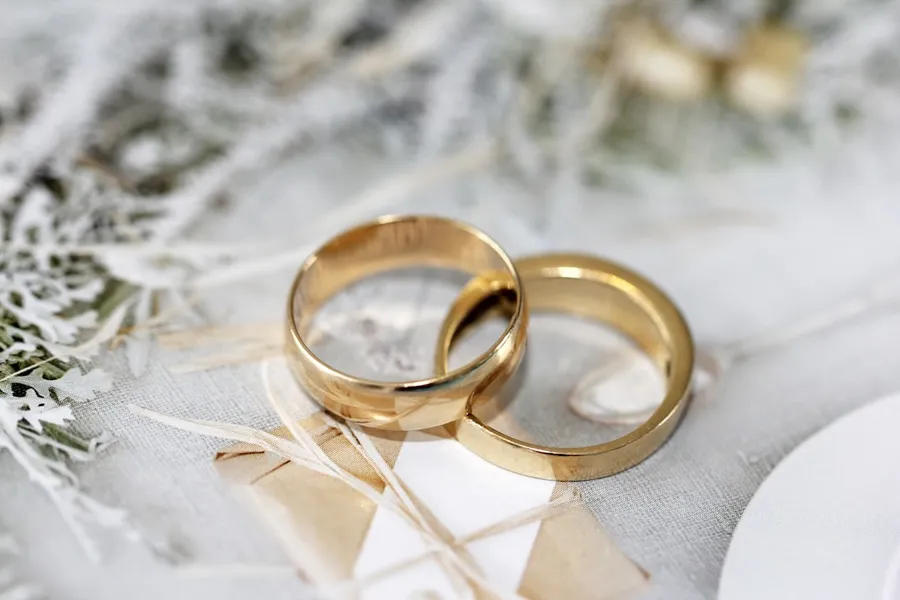 Ilustrasi mimpi jodoh — gold wedding band on white textile