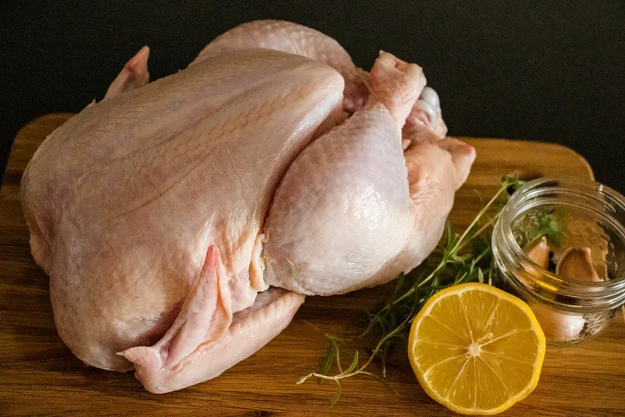 Ilustrasi mimpi jual ayam — raw chicken meat on brown wooden chopping board