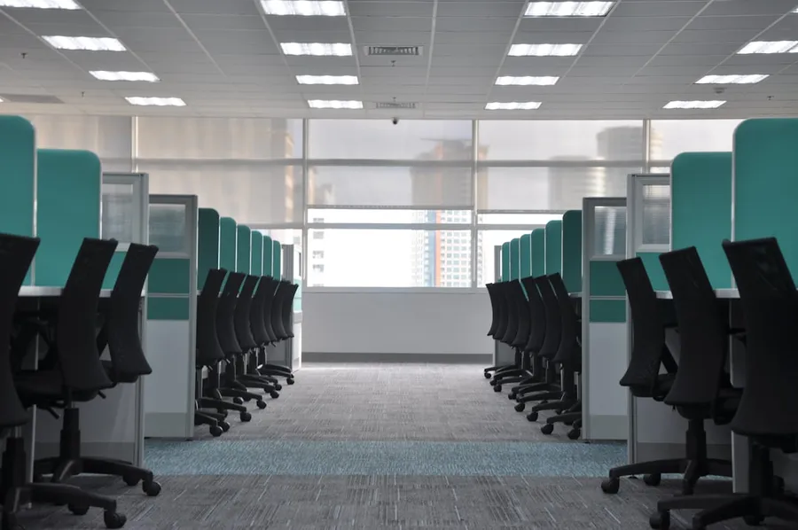 Ilustrasi mimpi kantor pln — empty black rolling chairs at cubicles