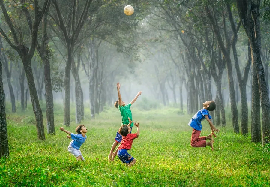 Ilustrasi mimpi kasti — four boy playing ball on green grass