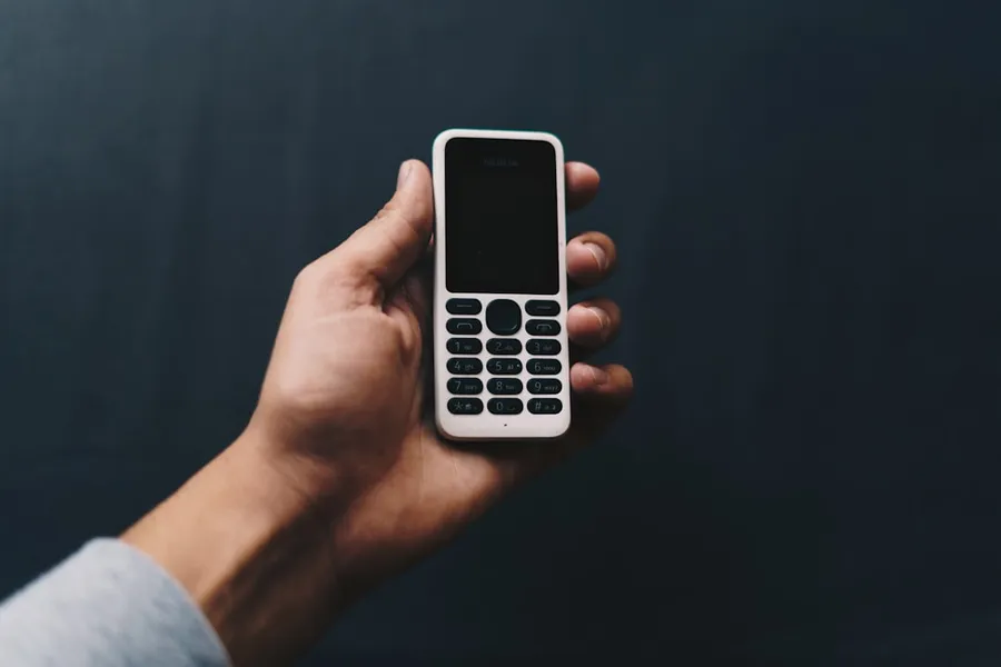 Ilustrasi mimpi kehilangan hp — person holding white qwerty phone