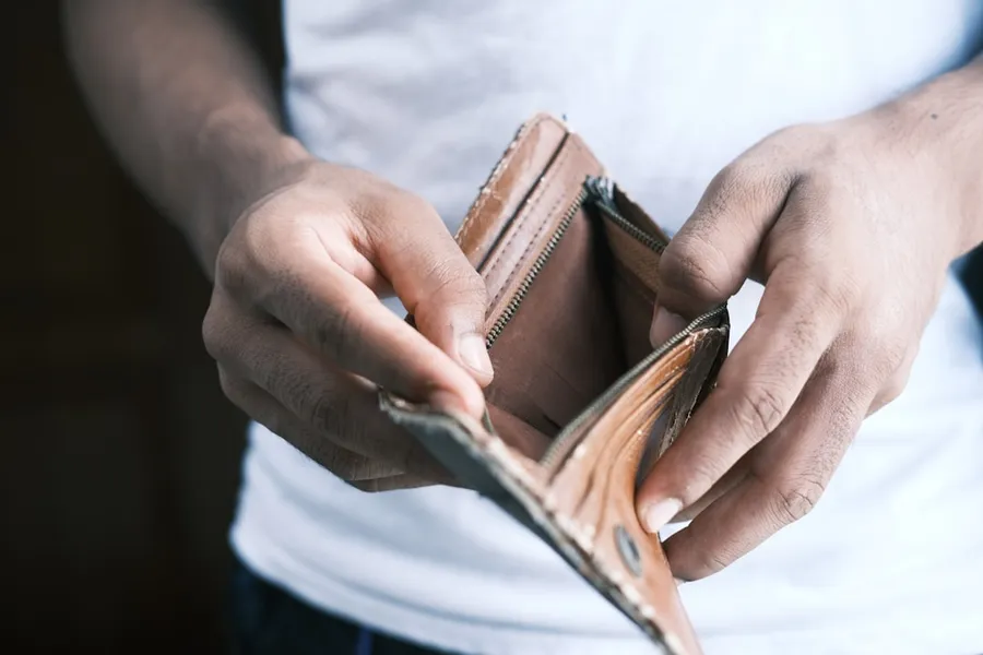Ilustrasi mimpi kehilangan uang — person holding brown leather bifold wallet
