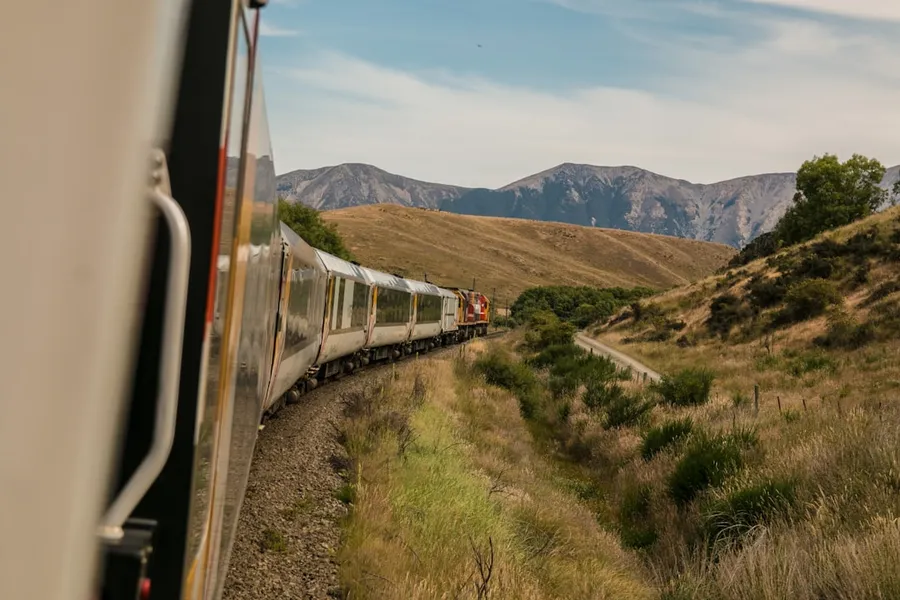 Ilustrasi mimpi kereta sampah — white train with the distance of mountain during daytime