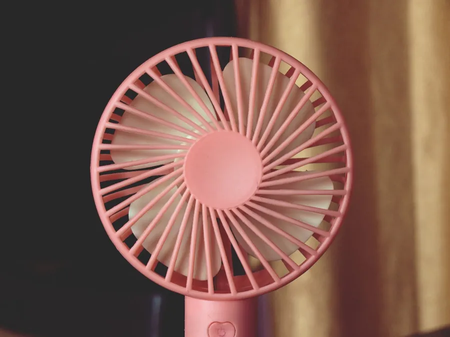 Ilustrasi mimpi kipas angin — A pink fan sitting on top of a table
