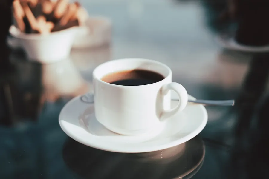 Ilustrasi mimpi kopi hitam — cup of coffee on white ceramic saucer