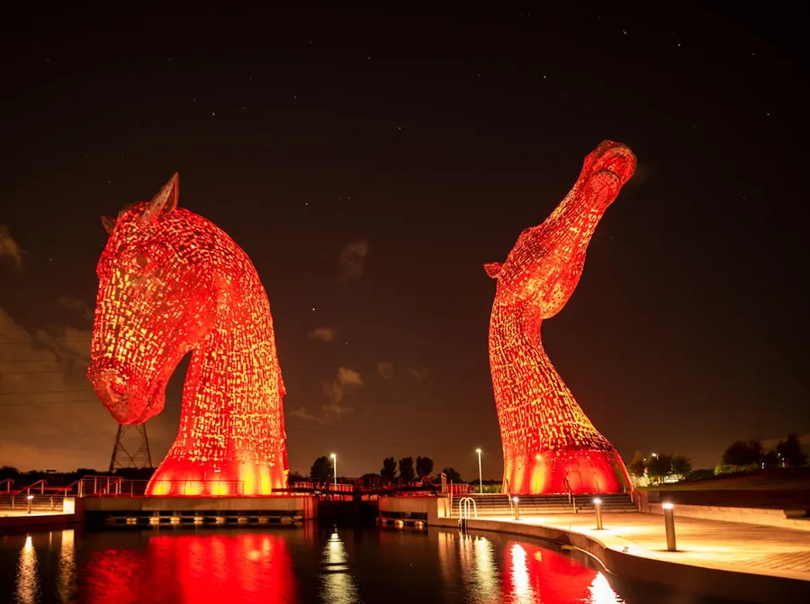 Ilustrasi mimpi kuda merah — red dragon statue near body of water during night time