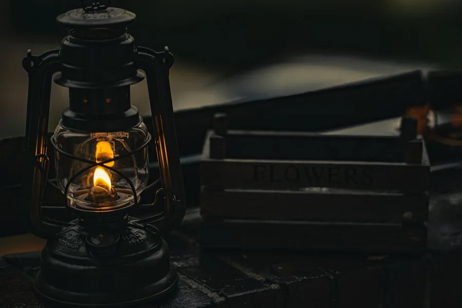 Ilustrasi mimpi lampu minyak — black lantern on black wooden table