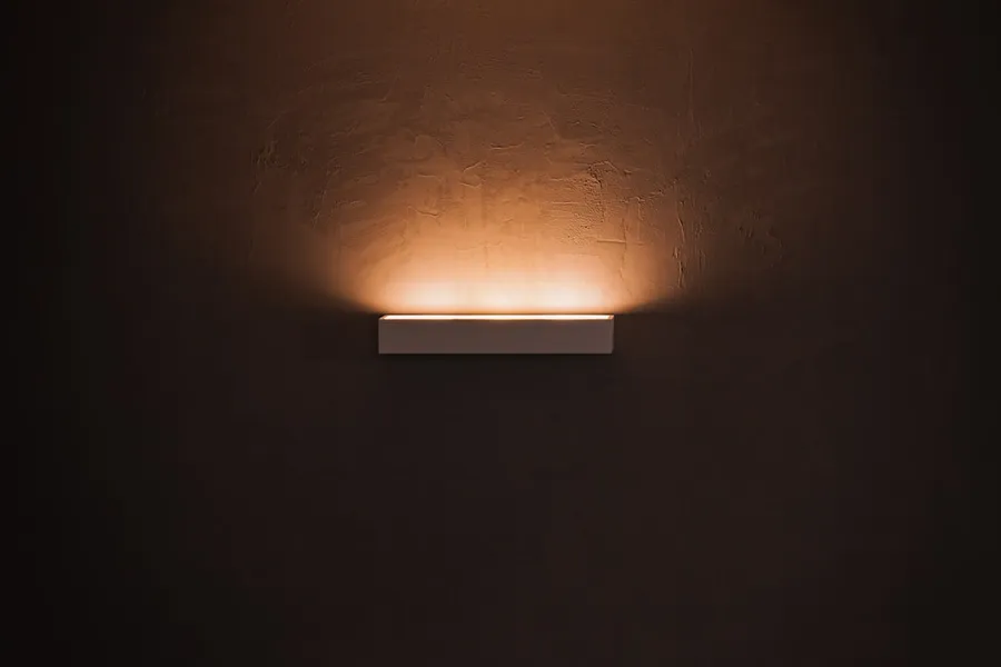Ilustrasi mimpi lampu otomatis — white light bulb turned on in dim lit room